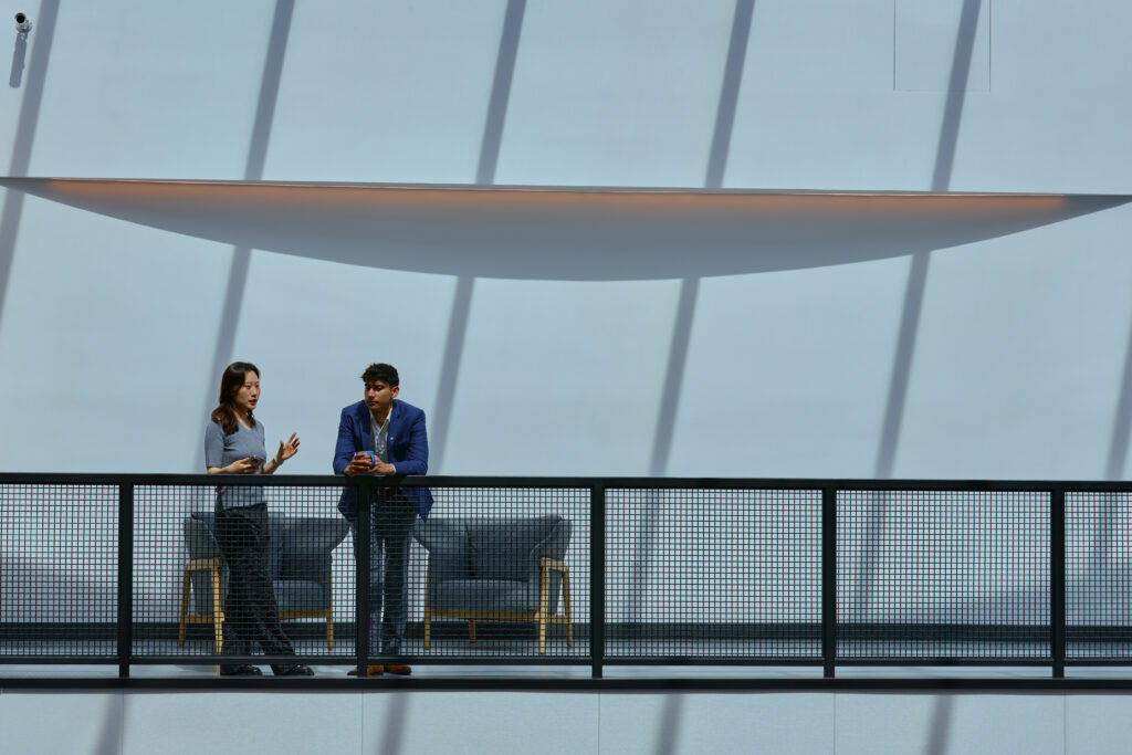 Two people standing against a metal railing.
