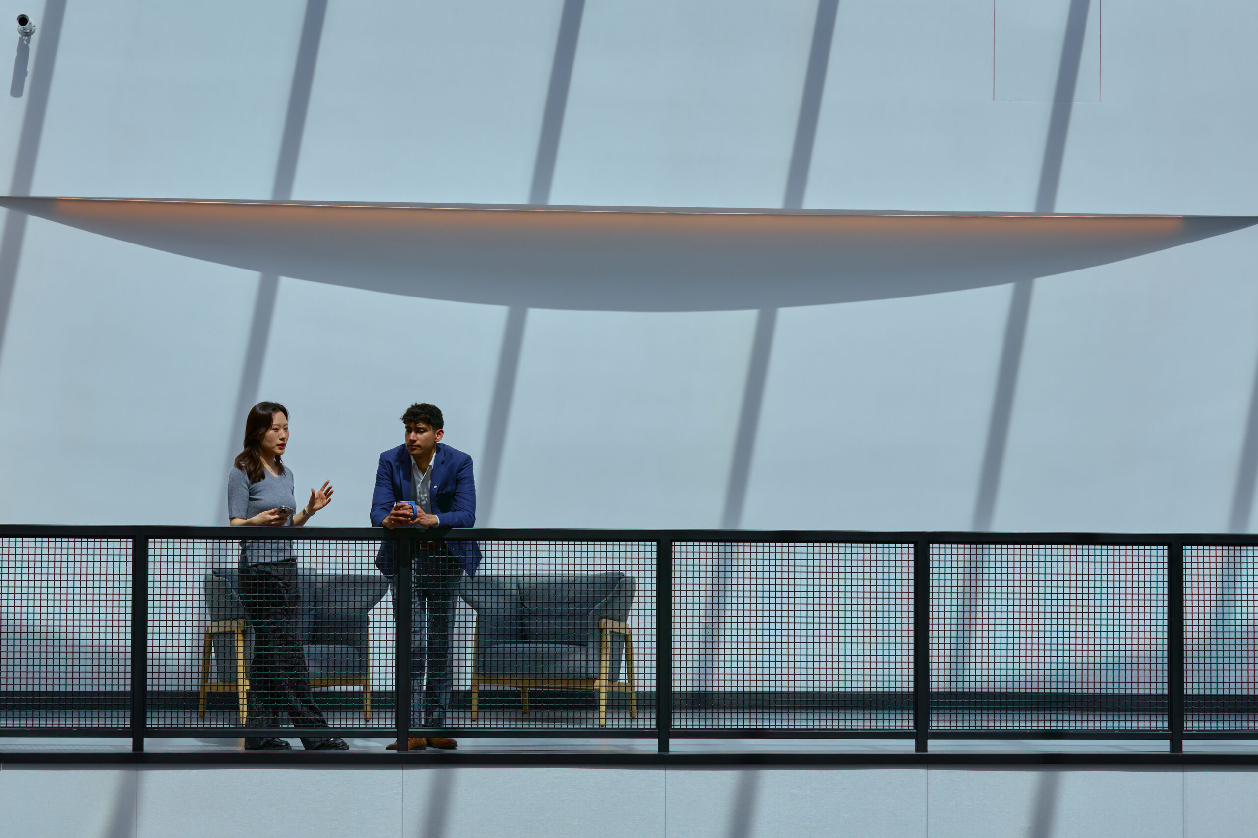 Two people standing against a metal railing.